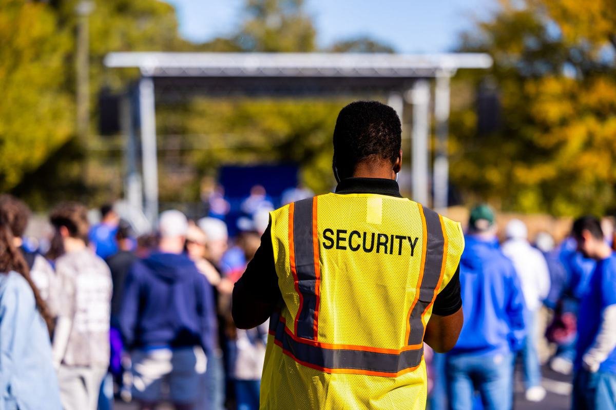 A security steward in a high-visibility vest watching over an event crowd
