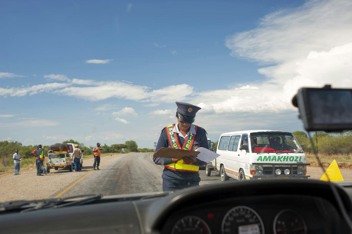 A traffic officer in a high-visibility vest at a roadside check