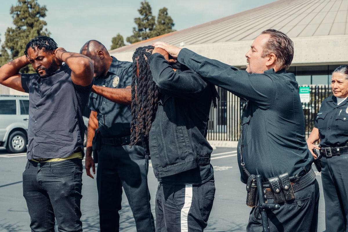 Officers working as a team to control standing people with their hands on their heads