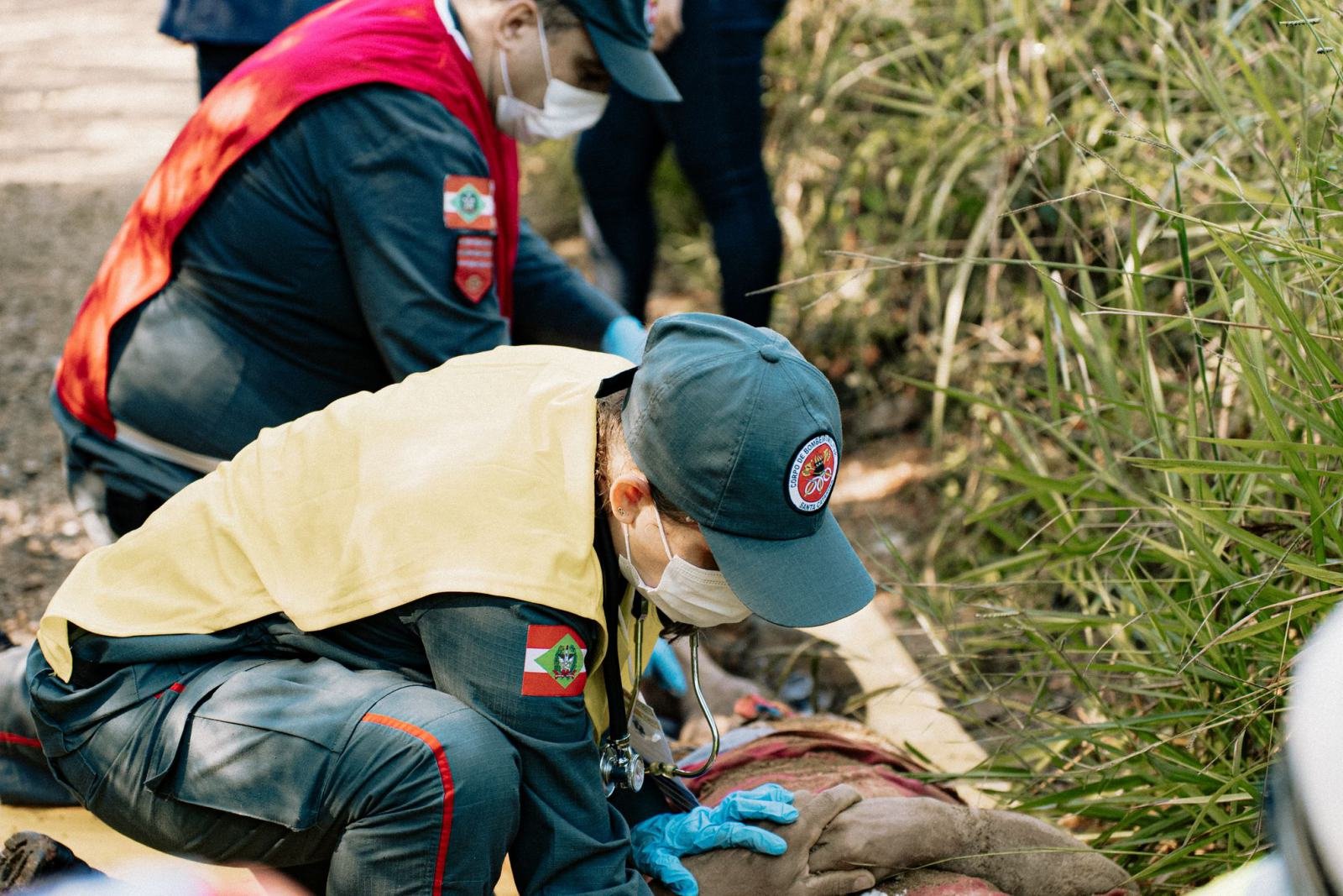 Uniformed responders kneeling to practise an emergency scenario with a person on the ground
